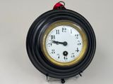 une horloge noire et dorée entourée d'un ruban rouge