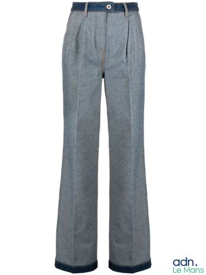 Cette femme porte un pantalon gris et une chemise blanche.