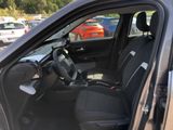 the interior of a car with the door open and a steering wheel in the passenger seat
