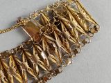 an image of a close up of a gold bracelet on a white surface