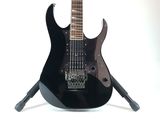 a black electric guitar on a stand on a white background