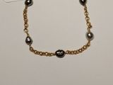 a gold bracelet with black pearls on a gold chain