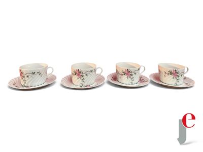 quatre tasses et soucoupes sont alignées sur une surface blanche