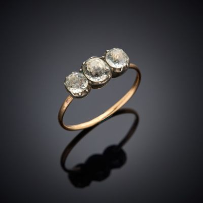 une bague en or sertie de trois diamants blancs sur fond noir