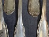 six silver spoons are lined up on a black cloth