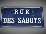 blue sign with white writing on it saying rue des sabotts