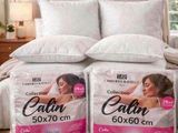 deux oreillers posés sur un lit, sur lesquels est représenté le visage d'une femme