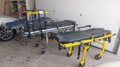 une civière jaune posée dans un garage à côté d'une voiture blanche