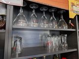 bottles and glasses are lined up on a shelf in a bar