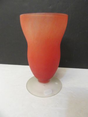 un vase en verre aux couleurs vives posé sur une table blanche devant un mur noir