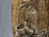 a brown vase with a bear on it sitting on a tree branch