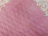 a close up of a pink quilt on a bed