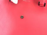 the person is holding a red handbag with a button on it