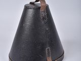 a black bell on a white surface with a brown strap