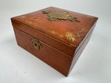a small wooden box with a gold decoration on it