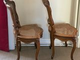 pair of wooden chairs with cane backrests in a room with a red curtain