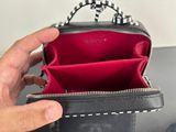someone is holding a black purse with a chain hanging out of it
