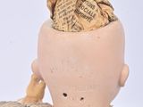 a small doll with a hat on it ' s head and a piece of newspaper in it ' s hair