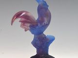 a purple and blue bird statue on a black base