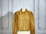une veste jaune posée sur un mannequin devant un mur blanc