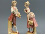 deux figurines représentant un homme et une femme avec des paniers de fleurs