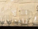 Des bouteilles et des verres sont alignés sur une étagère devant un mur de briques.