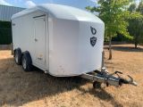 a white trailer parked in a field with trees in the background