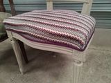 a white chair with a purple and white striped cushion on it