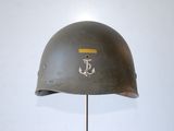 an old helmet with a anchor on it is on a stand