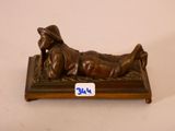 figurine en bronze représentant un homme allongé sur un banc, coiffé d'un chapeau