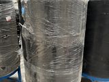 several large black barrels are wrapped in plastic and stacked on top of each other