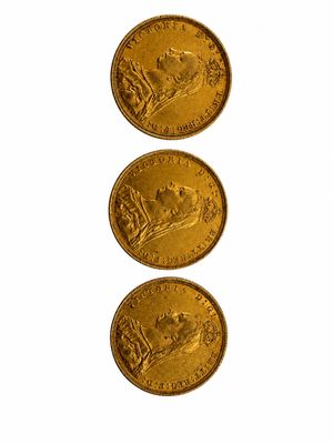 trois pièces d'or sont disposées en ligne sur une surface blanche