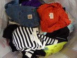 a pile of clothes in a laundry basket on a bed