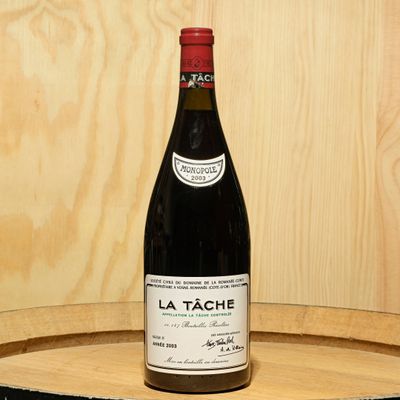 a bottle of wine sitting on top of a wooden barrel