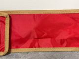 un sac rouge orné d'une bordure dorée posé par terre