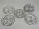six assiettes en verre transparent posées sur une table blanche, sur fond blanc