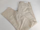 un pantalon beige posé sur une surface blanche, avec un fond blanc