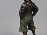 bronze statue of a boy with a basket on his head