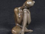 statue of a woman sitting on a rock on a black background