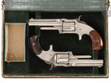 deux revolvers en argent dans une boîte verte avec un étui en cuir