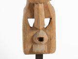 une photo d'une sculpture en bois représentant le visage d'un homme, posée sur un socle