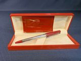 une boîte rouge contenant un stylo, posée sur une surface bleue