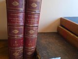 two old books are sitting on a table next to a book case