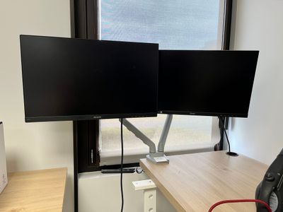 deux écrans posés sur un bureau devant une fenêtre