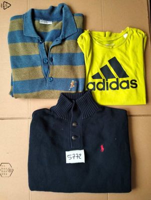 three shirts and a polo shirt are sitting on a cardboard box