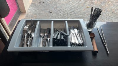 a tray with forks and spoons in it on a table