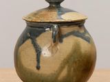 a brown and blue vase with a lid on a table