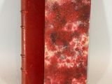 un vieux livre à la couverture rouge posé sur une table blanche