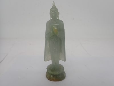 une petite statue de Bouddha posée sur une surface blanche