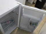 a small white refrigerator sitting in the corner of a kitchen